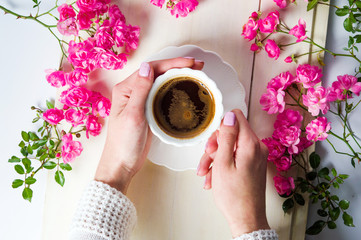 Wall Mural - Girl having a cup of tea on table with roses