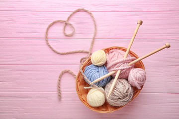 Wall Mural - Balls of knitting yarn in basket and heart made of thread on wooden background