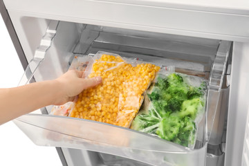 Wall Mural - Woman taking frozen vegetables from refrigerator, closeup