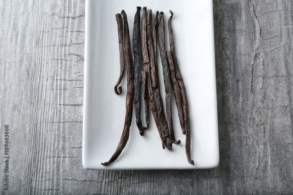 Plate with vanilla sticks on table