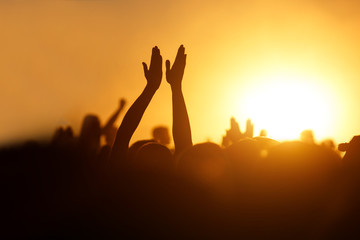 Rock concert, silhouettes of happy people raising up hands