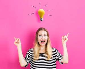Wall Mural - Young woman reaching and looking a yellow lightbulb