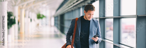 Photo: Smiling man looking at smart phone in airport Smiling man looking at smart phone in airport