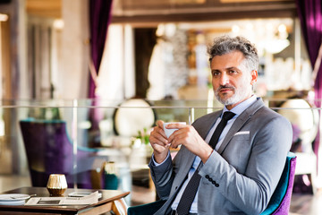 Wall Mural - Mature businessman with coffee in a hotel lounge.