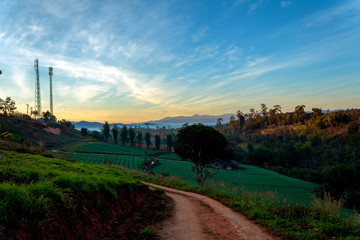 Mountain path and telecommunication tower on top of the mountain whit colorful sky at sunrise or sunset time.