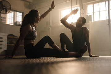 Man and woman giving high five in gym