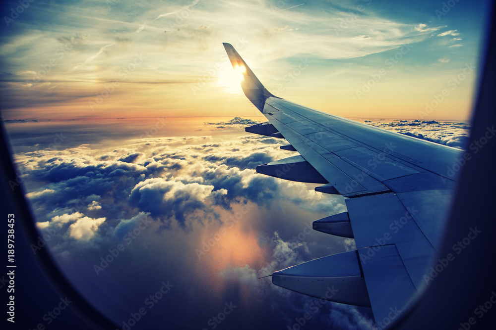flying and traveling,  view from airplane window on the wing on sunset time  - obrazy, fototapety, plakaty 