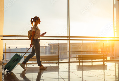 Cuadros en Lienzo young woman goes at airport at window with suitcase waiting for plane