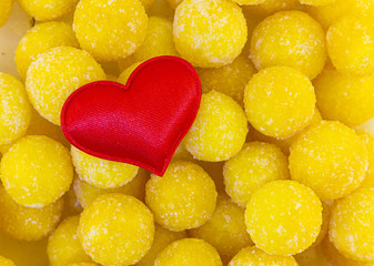 Wall Mural - symbol of love family red heart cloth on a background of candied yellow candy balls sweet. base postcard day valentine