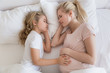 © LIGHTFIELD STUDIOS - top view of daughter and mother sleeping on bed