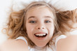 © LIGHTFIELD STUDIOS - top view of laughing adorable child lying on bed and looking at camera