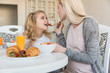 © LIGHTFIELD STUDIOS - pregnant mother feeding daughter in kitchen