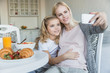 © LIGHTFIELD STUDIOS - smiling pregnant mother and daughter taking selfie in kitchen