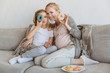 © LIGHTFIELD STUDIOS - happy pregnant mother and daughter having fun with donuts