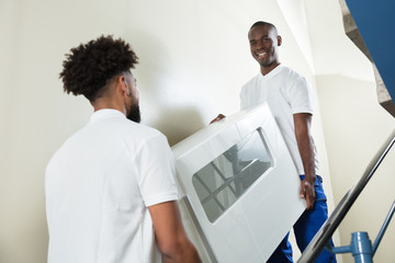 Wall Mural - Young Movers Carrying Cabinet While Climbing Steps