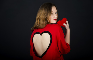 Valentines day love concept. Brunette young woman in red dress holding heart shape gift 