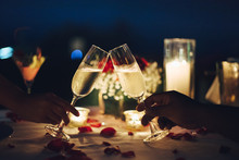Romantic Candlelight Dinner Table Setup For Couple With Beautiful Light As Background. Man & Woman Hold Glass Of Champaign. Concept For Valentine's Day And Date.
