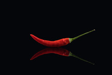 Hot Red Chili Pepper On The Black Glass Background