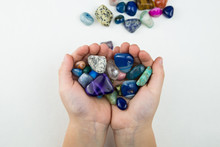 Child's Hands Holding A Few Semi Prescious Gemstone From A Pile Of Blue Green Stones