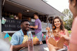 © Syda Productions - happy friends with drinks eating at food truck