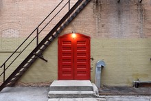 Red Wooden Double Door Entrance With A Stairway And Single Overhead Light