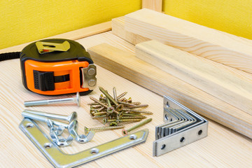 Woodwork tools and screws at the wood planks on yellow background