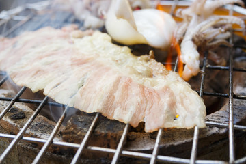 close up of sliced raw beef grilling on charcoal stove