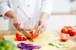 © pressmaster - Chef of restaurant cutting red pepper in two halves while cooking meal from vegs