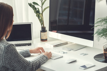 Young woman freelancer indoors home office concept casual style working on laptop and computer