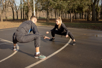  couple of young athlets do exercises outdoors in autumn park 