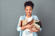 Young african woman isolated on grey wall studio casual daily lifestyle standing with books joyful