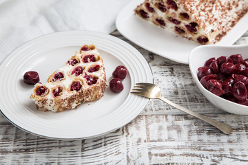 Wall Mural - cake with cherries, cream and chocolate on a light wooden background