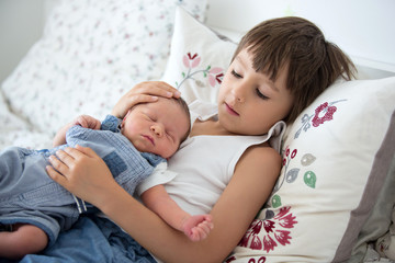 Wall Mural - Beautiful boy, hugging with tenderness and care his newborn baby brother at home