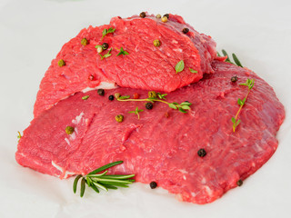 Wall Mural - raw beef with seasoning  rosemary, pepper  on white parchment paper, side view