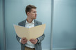 © Yakobchuk Olena - Work papers. Young man is holding documents while standing in office. He is looking aside seriously. Copy space in the right side