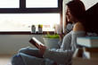 © lordn - Beautiful young woman at home drinking coffee reading a book