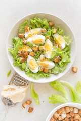 Wall Mural - Caesar salad with eggs, lettuce and parmesan cheese on plate. Top view