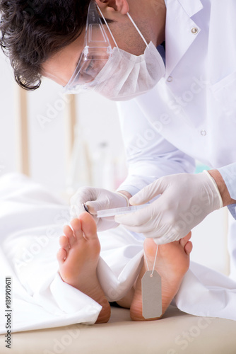 Fotografía Police coroner examining dead body corpse in morgue