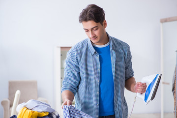 Young man husband doing clothing ironing at home