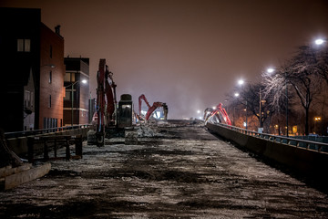 Night construction site of the city of Chicago's Western Avenue viaduct bridge featuring demolition machinery and bulldozers.