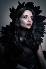 Wall Mural - Vertical beauty portrait in dark tones. Luxury young woman with black feathers in her hair