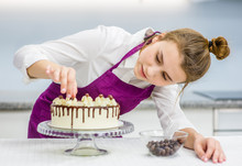 Young Woman Decorating Chocolate Cake In The Kitchen