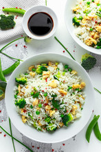 Fried Rice With Vegetables, Broccoli, Peas And Eggs In A White Bowl. Soy Sauce. Healthy Food