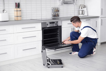 Young man repairing oven in kitchen