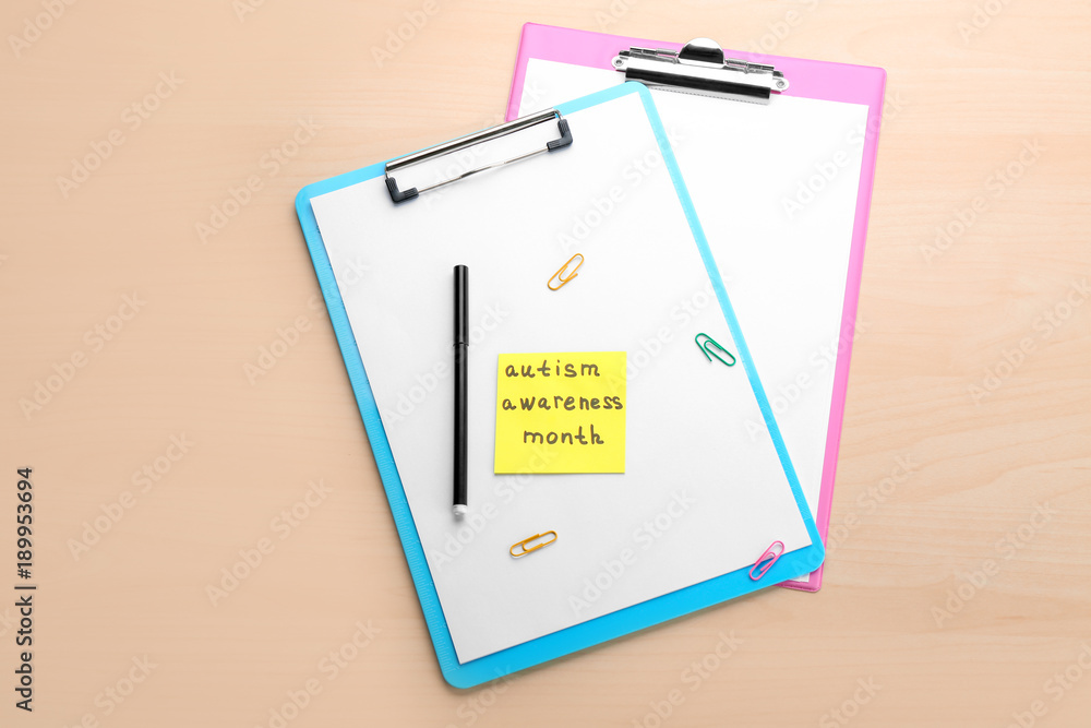Clipboards and note with phrase "Autism awareness month" on light background