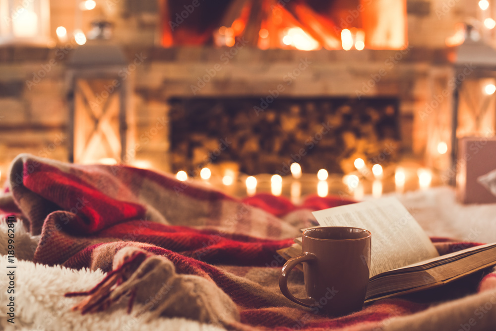 One cup and a book near the fireplace winter concept - obrazy, fototapety, plakaty 