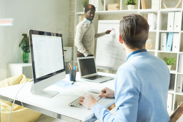 Portrait of two people, one of them African, collaborating on business project while working in modern office, copy space