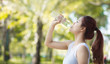 © chompoo - Young beautiful woman  drinking water at summer green park.