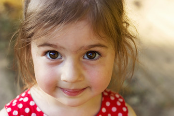 Cute little Girl looking at the camera  surprised. Happy Kid outdoors