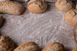 Tradycyjny chleb i bułki na zakwasie z szorstką skórką na rustykalnym drewnianym stole. 